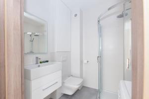 a white bathroom with a toilet and a shower at Raval Apartments - Fresh Turquoise in Rewal