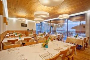 un restaurante con mesas y sillas blancas y una gran ventana en Agritur La Polentera en Storo