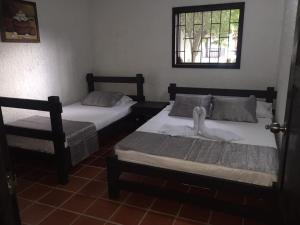 two beds in a room with a window at CABAÑAS SHALOM in San Gil
