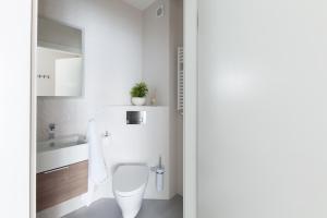 a white bathroom with a toilet and a sink at Raval Apartments - Soft Black in Rewal