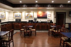 a restaurant with tables and chairs and a television on the wall at Homestead Lodge Apart Hotel in Pleasantville