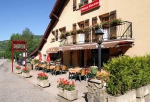a restaurant with tables and chairs and a balcony with flowers at Auberge Alsacienne in Bussang