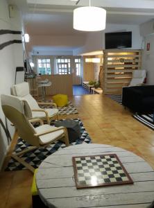 Albergue Puente para peregrinos في بوينتي لا رينا: غرفة بها كراسي وطاولة شطرنج على الأرض