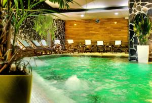 a pool in a hotel with chairs and a table at Hotel Grand Jasna in Demanovska Dolina