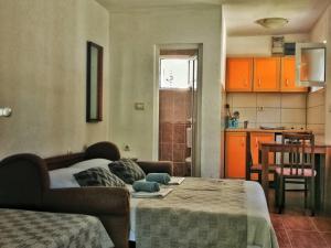 a room with a bed and a kitchen with orange cabinets at Vojinovic Apartments in Budva