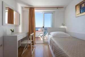 a bedroom with a bed and a desk and a window at Vila Nela in Tučepi