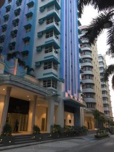 a tall blue building with palm trees in front of it at Travellers 101 Condo near Manila Airport in Manila