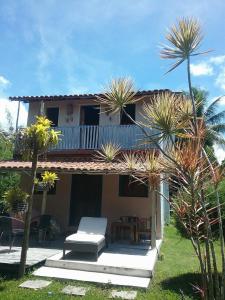 昆幕露夏其巴的住宿－Casa das Falésias Cumuruxatiba，一个带椅子和棕榈树阳台的房子