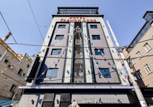 un edificio alto con una señal roja. en French code Hotel, en Changwon