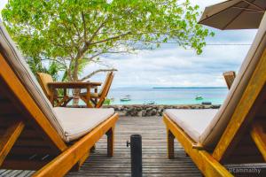 dos sillas y una sombrilla en una terraza con el océano en Bara Beach Bungalows, en Bira