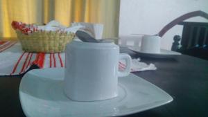 a white coffee cup on a plate on a table at Hotel Falcon in Tamasopo