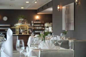 a dining room with white tables and chairs with wine glasses at Park Hotel Hamburg Arena in Hamburg