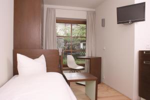 Schlafzimmer mit einem Bett, einem Schreibtisch und einem Fenster in der Unterkunft Apartment Mohren in Oberstdorf