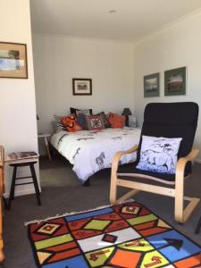 a bedroom with a bed and a chair and a rug at Entabeni in Raglan
