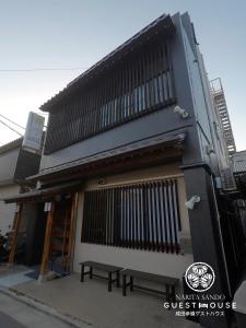 a building with a bench in front of it at Narita Sando Guesthouse in Narita