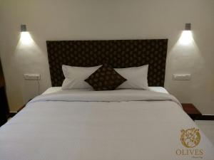 a bedroom with a large bed with white sheets and pillows at Olives Pleasant Stays in Ooty