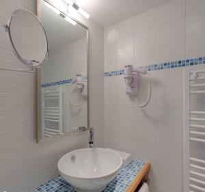 a white bathroom with a sink and a mirror at Hôtel la Croix Blanche in Le Mont Saint Michel