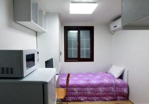 a small room with a bed and a microwave at Laketel in Seoul