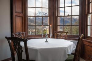 una sala da pranzo con tavolo e vista sulle montagne di Glencoe House a Glencoe