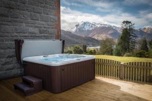 uma banheira de hidromassagem num deque com montanhas ao fundo em Glencoe House em Glencoe