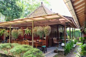een houten pergola met een tafel in een tuin bij Cempaka Borobudur Guest House in Borobudur
