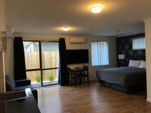 a bedroom with a bed and a desk and a window at Uni Motel in Hamilton