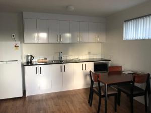a kitchen with white cabinets and a table and a refrigerator at Uni Motel in Hamilton