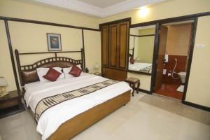 a bedroom with a large bed and a bathroom at Lytton Hotel in Kolkata