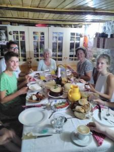 Un groupe de personnes assises autour d'une table avec de la nourriture dans l'établissement Cottage Poe, à Poienari