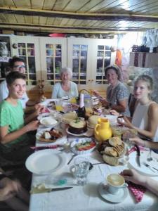 un grupo de personas sentadas alrededor de una mesa con comida en Cottage Poe, en Poienari