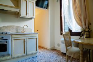 a kitchen with white cabinets and a table and a window at Melusina Rialto Venice Center in Venice +2 photos