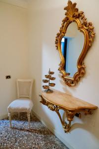 a mirror on a wall with a table and a chair at Melusina Rialto Venice Center in Venice