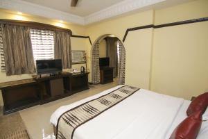 a bedroom with a large bed and a television at Lytton Hotel in Kolkata