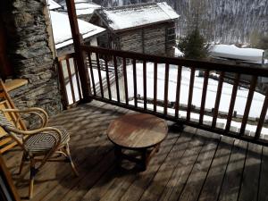 a wooden table and chair on a deck with snow at le berger gourmand in Saint-Véran