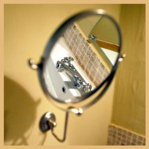 einen Spiegel, der ein Waschbecken im Bad reflektiert in der Unterkunft B&B Hoeve de Steenoven in Damme