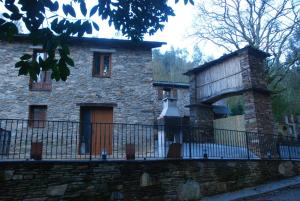 una vieja casa de piedra con una valla delante de ella en Isabel Artemis ES, en San Tirso de Abres