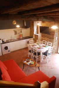 cocina y sala de estar con sofá rojo y mesa en Isabel Artemis ES, en San Tirso de Abres