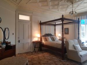 - une chambre avec un lit à baldaquin et une chaise dans l'établissement Blair Athol Homestead, à Inverell