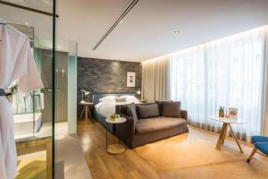 a bedroom with a bed and a couch and a chair at Ad Lib Hotel Bangkok in Bangkok +104 photos