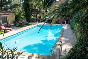 a blue swimming pool with a palm tree next to a house at Domaine Jobert in Aubagne