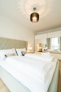 sypialnia z dużym białym łóżkiem i lustrem w obiekcie Vienna Residence | Spacious Serviced Apartment in Vienna directly at the U4 w Wiedniu