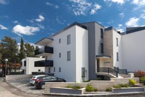 a white building with cars parked in a parking lot at Orfeo in Krk
