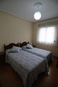 a bedroom with two beds with blue blankets and a light at La Nogalera in Nueva de Llanes +19 photos