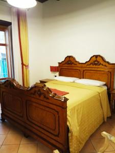 a bedroom with a large wooden bed with yellow sheets at Amalfitani Salerno Centro in Salerno