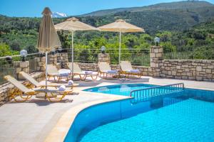 a swimming pool with chairs and umbrellas next to at Villa Tinadora in Agia Triada