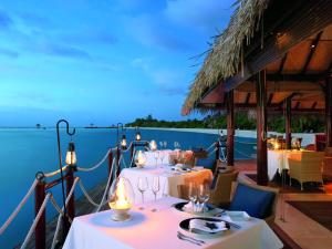 a dining room table with chairs and umbrellas at Taj Exotica Resort & Spa in South Male Atoll