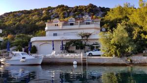 a boat is docked in front of a house on the water at Apartments Livia in Lastovo
