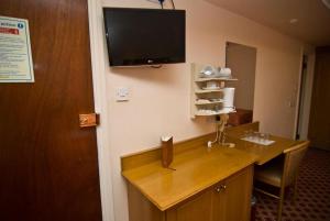 a room with a desk with a television on the wall at Seymour Hotel in London