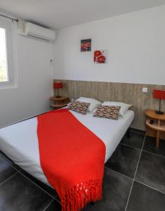 a bedroom with a bed with a red blanket on it at Macchie e Fiori in Pianottoli-Caldarello