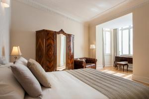 - une chambre avec un grand lit blanc et une chaise dans l'établissement Luxury at Liberdade - In the heart of Lisbon, à Lisbonne
